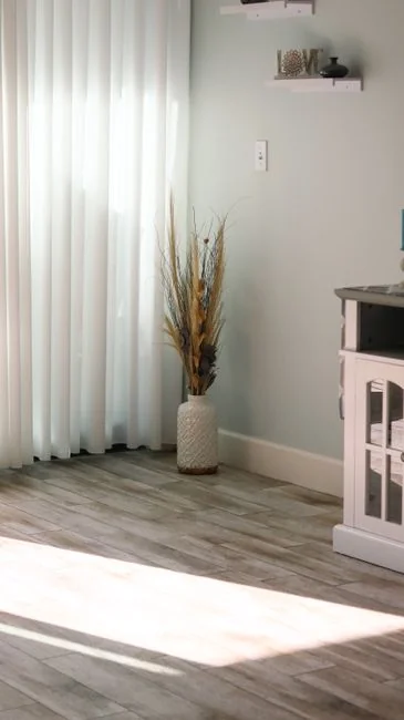 A woman in overalls cleans a wall in a stylish living room, enhancing home hygiene.